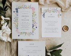 the wedding stationery is laid out with flowers and greenery