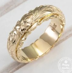 a gold wedding band with flowers on it