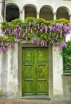 a green door with purple flowers growing over it