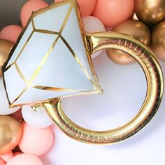 a white and gold ring sitting on top of balloons