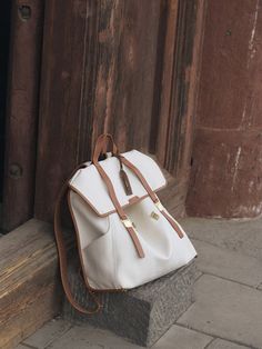 a white purse sitting on top of a stone block next to a wooden door with a brown handle