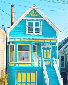 a blue house with yellow and white trim on the front, stairs leading up to it