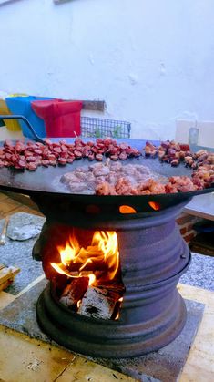 an outdoor grill with food cooking on it's sides and fire in the middle