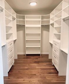 an empty walk in closet with white shelving and wood flooring on the wooden floor