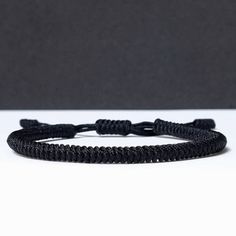 a black rope bracelet on a white surface