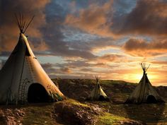 three teepees sitting in the grass at sunset