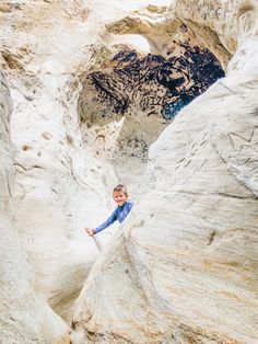 a young boy standing on top of a rock formation in the middle of a canyon