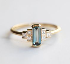 an emerald and diamond ring on a white surface