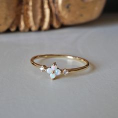 This dainty Forget Me Not ring features four natural Australian opal hugged between two natural diamonds. Set on a polished dainty band. A beautiful ring to wear on your finger to remind you of the beauty of life. Crafted in 14K solid gold in our NYC studio. 14K solid gold Natural Australian opals and diamonds 1.2mm ring band ** This item is specially made for you. Please allow 1-2 week lead time. Shipping:Domestic: Free standard shipping within the U.S.International: Free standard shipping for Delicate 14k Gold Opal Ring, Delicate White Opal Ring In 14k Gold, Delicate Yellow Gold Opal Ring, Forget Me Not Ring, Opal And Sapphire Ring, Forget Me Not Flower, The Beauty Of Life, Dainty Band, Nyc Studio