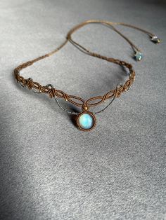 a necklace with an opalite stone is displayed on a gray surface, close - up