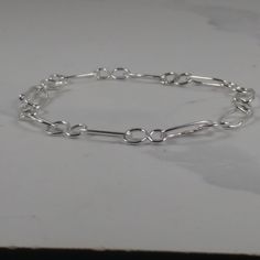 Every link in this silver chain is soldered for strength, with a hand-made silver hook and eye fastening to keep it securely on your wrist. The design features figure-of-eight shapes linked by ovals of round section sterling silver wire. You can adjust the length to suit your wrist by linking the hook into different eyes. Sterling Silver Link Paperclip Bracelet, Sterling Silver Paperclip Link Bracelet, Silver Sterling Silver Link Paperclip Bracelet, Sterling Silver Link Chain Bracelet, Silver Chain Bracelet With Hook And Links For Everyday, Minimalist Chain Bracelet With Hook And Links, Minimalist Chain Bracelet With Hooks And Links, Elegant Sterling Silver Bracelet With Hook And Links, Minimalist Chain Bracelet With Hook And Links As Gift