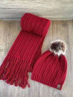 the red scarf and hat are laying on the floor next to each other with a pom - pom