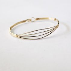 Here's an elegant and versatile square wire bracelet, a must-have addition to your jewelry collection. Crafted with four plain square 14kt gold filled wires, this spread-open design offers a head-turning and feminine look that is both timeless and chic. Its simplicity makes it perfect for stacking with other bangles, creating your own unique style statement. The built-in hook and eye-type clasp ensures easy wearability, allowing you to quickly put it on and take it off. This bracelet is designed Adjustable Bangle With Bracelet Strap For Everyday, Adjustable Everyday Bangle With Bracelet Strap, Adjustable Everyday Bangle, Adjustable Minimalist Bangle Bracelet, Adjustable Gold Bangle Bracelet For Everyday, Adjustable Minimalist Brass Bracelets, Adjustable Nickel-free Minimalist Bangle, Minimalist Adjustable Brass Bracelets, Adjustable Modern Gold Bangle Bracelet