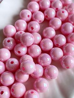 some pink beads are on a white plate and there is no image in the top right corner