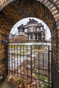 an old brick building with a gate in the foreground and snow on the ground