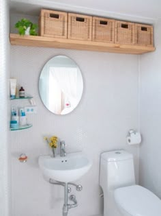 a bathroom with a toilet, sink and shelf above the toilet is shown in this image