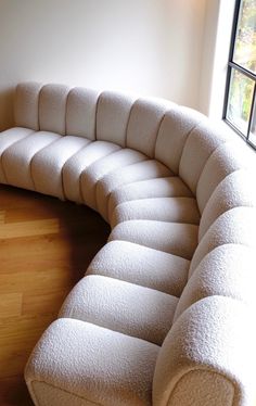 a curved couch sitting on top of a hard wood floor