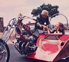 two women sitting on the back of a motorcycle with a side car attached to it