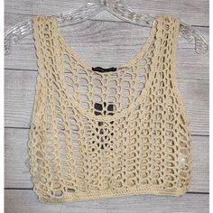 a crocheted crop top hanging on a wooden hanger with an openwork design