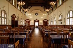 an empty dining hall with wooden tables and blue tablecloths on the tables in front of them