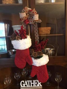 two christmas stockings hanging from a shelf with wine glasses