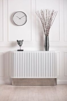 a white radiator in a room with a clock on the wall behind it