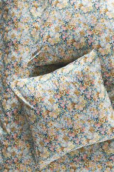 two pillows sitting next to each other on top of a bed covered in floral sheets