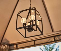 a chandelier hanging from the ceiling with three lights on it and an open window in the background