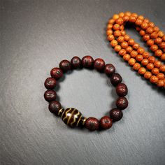 This unique Dalo Dzi bracelet combines the mysterious and unique qualities of the Fortune Wave dalo dzi and 15 old bodhi seed beads,giving it a distinct feel.It is brown in color and has a circumference of approximately 7 inches, suitable for most wrist sizes.This bracelet can be worn not only as a fashionable accessory but also holds cultural and religious significance.Dzi beads are precious jewelry from Tibetan culture which are believed to possess the power of bringing good fortune to the own Holistic Wooden Beads Bracelets For Meditation, Hand Wrapped Brown Beaded Bracelets For Meditation, Traditional Hand Wrapped Brown Bracelet, Brown Wooden Beads Bracelet, Handmade Brown Beaded Bracelets For Ceremonial Use, Handmade Traditional Brown Bracelets, Brown Wooden Beads For Bracelets, Handmade Brown Beaded Bracelets For Rituals, Spiritual Brown Beaded Bracelets