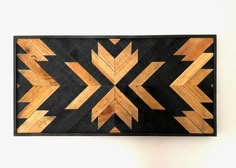 a wooden wall hanging on the side of a white wall with an arrow design in it