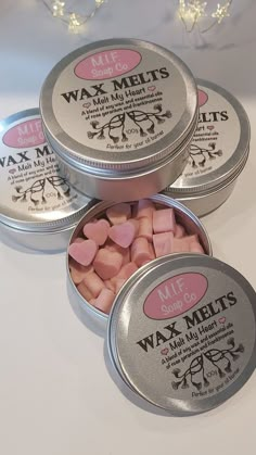 three tins of wax melts sitting next to each other on a white table