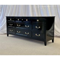 an antique black dresser with brass handles and knobs on the drawers is shown in front of a white curtain