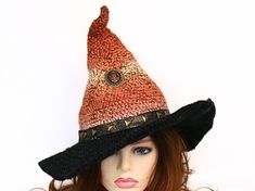 A little touch of edgy Goth in this witch or wizard hat just adds to the fun! Ready for the Renfair, cosplay, a LARP event, a costume, or just because you love all things mystical and magical. This hat is firmly shaped and will stand on its own. Soft to wear and easy to shape. I crocheted this in shades of dark rusty orange and brown, and the tip is naturally crooked. A beautiful vintage metal and enamel cabochon pin is attached mid-center. The wide black brim is wired so you can play with the shape for that perfect look, and highlighted with a faux leather studded hat band. Folds flat for travel. -This soft witchy hat has some stretch so it will fit between 21" to 23.5" head circumference. -3.5" brim How to measure your head: - Using a fabric tape measure or a string, place it flat agains Witchy Costume Hat For Fall, Handmade Halloween Costume Hat With Curved Brim, Handmade Curved Brim Hat For Halloween, Handmade Mini Hats With Curved Brim For Costume, Handmade Halloween Hat For Costume Party, Witchy Adjustable Costume Hats For Fall, Handmade Adjustable Halloween Costume Hats And Headpieces, Handmade Adjustable Costume Hats For Halloween, Adjustable Handmade Halloween Costume Hats And Headpieces