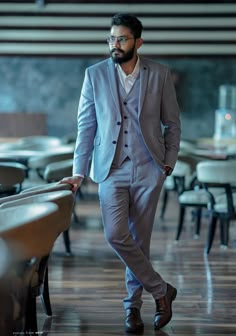 a man in a suit and tie standing next to a table