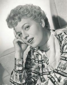 an old black and white photo of a woman with her hand on her chin looking at the camera