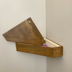 a wooden shelf with an open book on it and a metal object in the corner