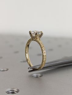 a diamond ring sitting on top of a tabletop with drops of water around it