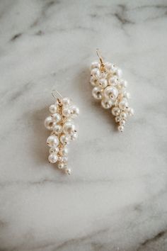 Valencia Earrings For the whimsical and fearless bride, these fun and lightweight pearl earrings add the perfect finishing touch to your wedding day look. Dozens of ivory pearls and crystal gems shimmer on these oversized drop clusters.  Make a bold statement with these standout earrings. Finished with a hook closure. Dimensions: Earrings are 7.5 cm long and approximately 3 cm wide. Our earrings, necklaces and bracelets are lead, nickel and cadmium free. These pieces are hypo-allergenic and are Fun Wedding Earrings, White Pearl Charm Drop Earrings For Bridal, White Pearl Charm Drop Bridal Earrings, Gift White Pearl Chandelier Earrings, White Pearl Embellished Earrings For Anniversary, White Pearl Drop Cluster Earrings For Anniversary, White Pearl Charm Chandelier Earrings For Wedding, White Cluster Earrings With Pearl Drop For Gift, White Cluster Earrings With Pearl Drop For Party