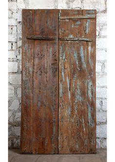 an old wooden door with peeling paint on it and brick wall in the back ground