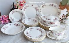 a table topped with lots of white plates and bowls filled with flowers on top of it