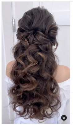 the back of a woman's head with long curly hair in half updo