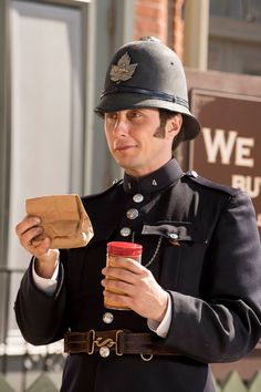 a man in uniform is holding a drink and looking at the paper bag he has placed in his hand