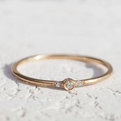 a gold ring with three diamonds on it sitting on a white surface in front of the camera