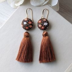 "Embody the fun vibes of the 1970s with these unique retro earrings - they're handmade with vintage fabric with a pretty floral print in shades of orange, brown, white, and green, with shiny and silky burnt orange tassels that hang below. You'll love the boho charm these earrings will add to your contemporary look, and how comfortable and lightweight they are, as well.  To complete the look, the earrings include hypoallergenic and nickel-free gold-plated brass earwires that provide a touch of elegance and ensure comfortable wear throughout the day. They'll also include small, clear rubber backings. Details: Full length - almost 3.5 inches (8.8 cm) Width of floral piece - 3/4\" (1.9 cm) Earring hooks - gold plated brass, hypoallergenic and nickel-free  Similar jewelry: Check out my shop for Retro Dangle Earrings For Festivals, Vintage Latkans Earrings For Party, Vintage Brown Earrings For Festivals, Vintage Multicolor Latkan Earrings, Vintage Tassel Jewelry For Festival, Bohemian Fall Fashion, 70s Earrings, Fun Vibes, Fall Fashion Accessories