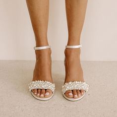 a woman's feet in high heel sandals with pearls on the toe and ankle