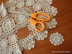 an orange pair of scissors sitting on top of a doily