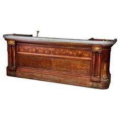 an antique wooden bar with marble top and brass trimmings on the front, in walnut