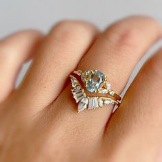 a woman's hand holding a ring with an aqua topazte and diamond accents