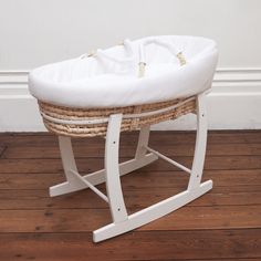 a white rocking toy with a basket on the seat and wood floor next to it