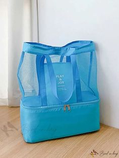 a blue tote bag sitting on the floor next to a white wall and window